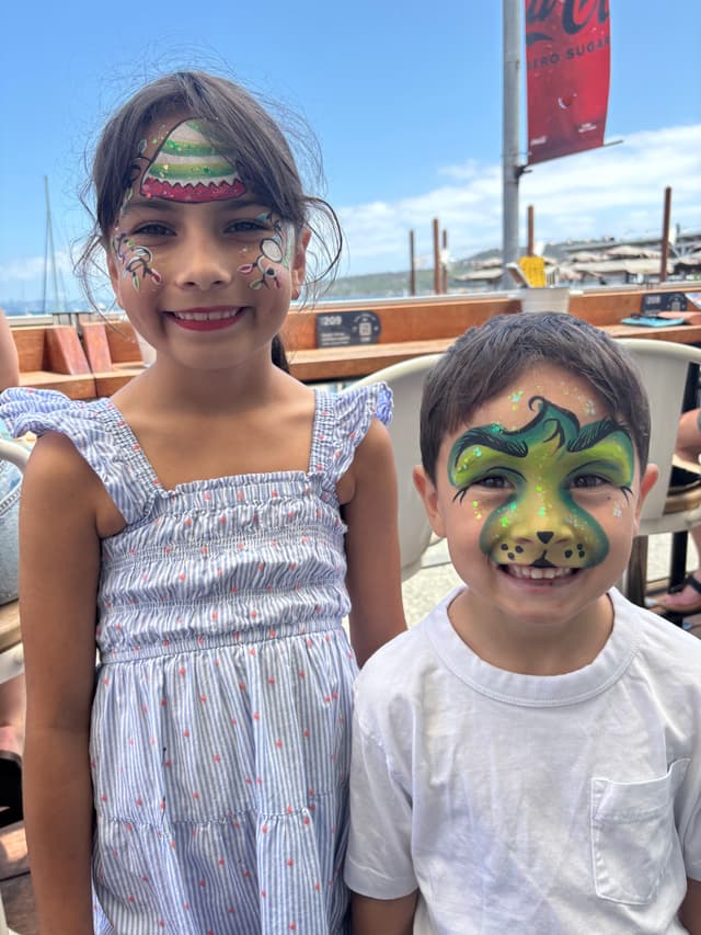 Two kids with elf and green cat face paint at the waterfront
