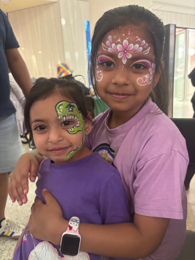 Two sisters with dinosaur and flower face paint